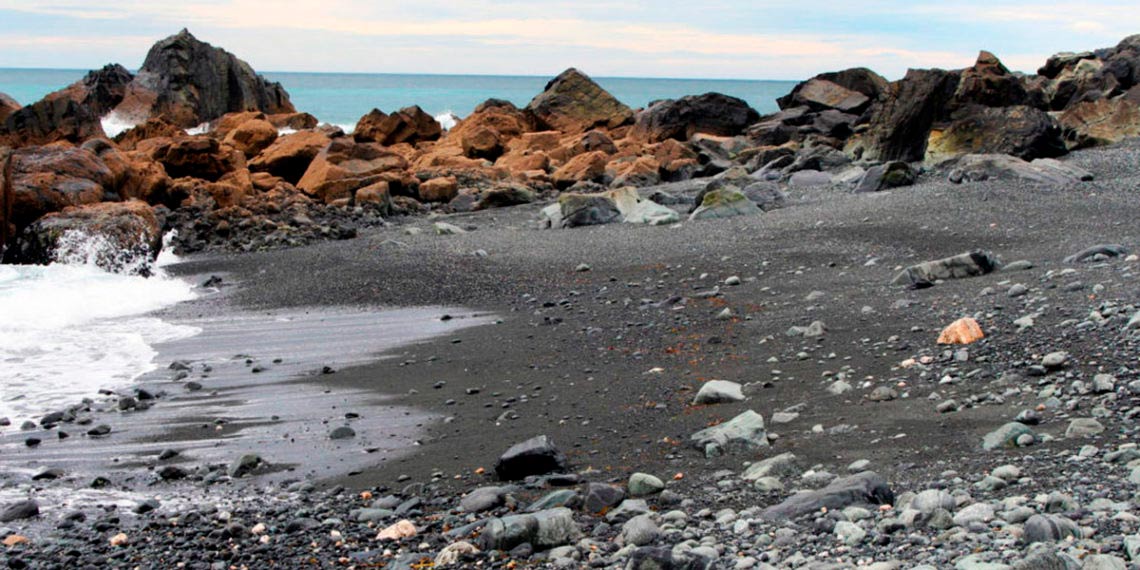 Praia de Área Negra en Cedeira con arena oscura y formaciones rocosas en la costa atlántica